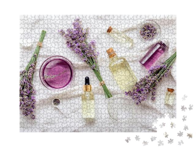 Puzzle 1000 Teile „Lavendelölserum und Lavendelblüten auf weißem Stoff, Spa, Schönheit“