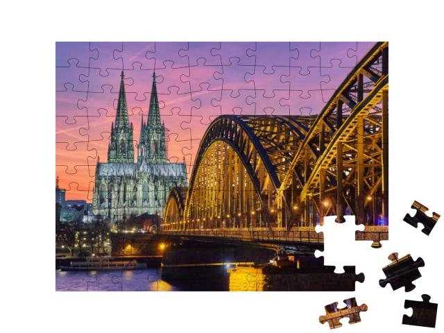 Puzzle 100 Teile „Kölner Dom und Hohenzollernbrücke bei Sonnenuntergang“